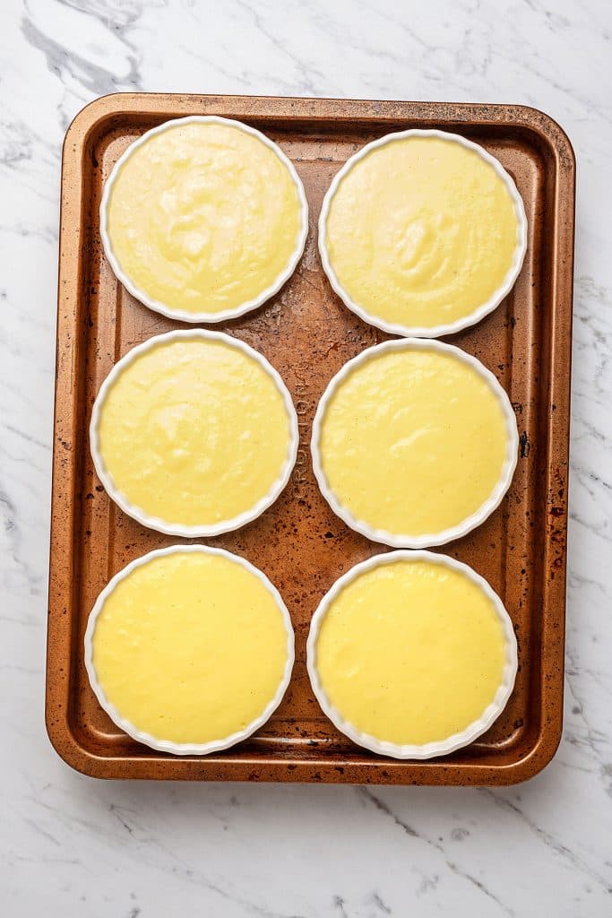 six ramekins with cream catalana in a baking tray