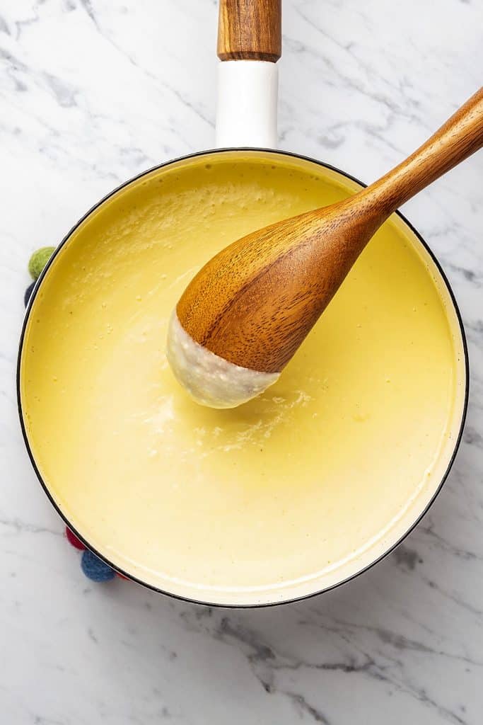 stirring a thickened custard mixture with a wooden spoon.