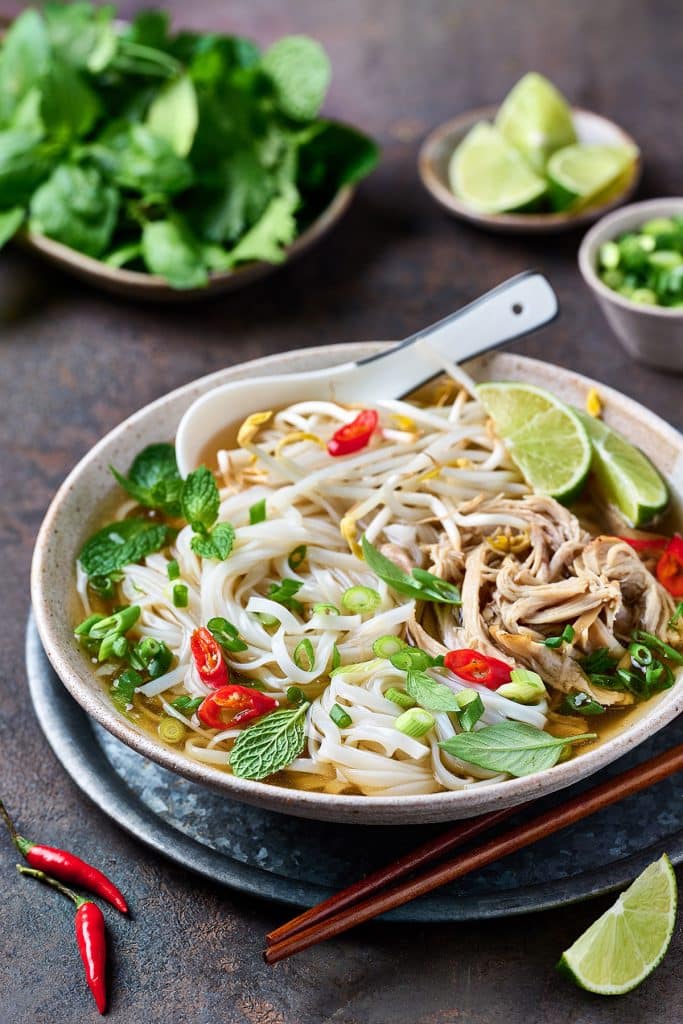 A big bowl of warming chicken pho topped with bean sprouts and herbs.