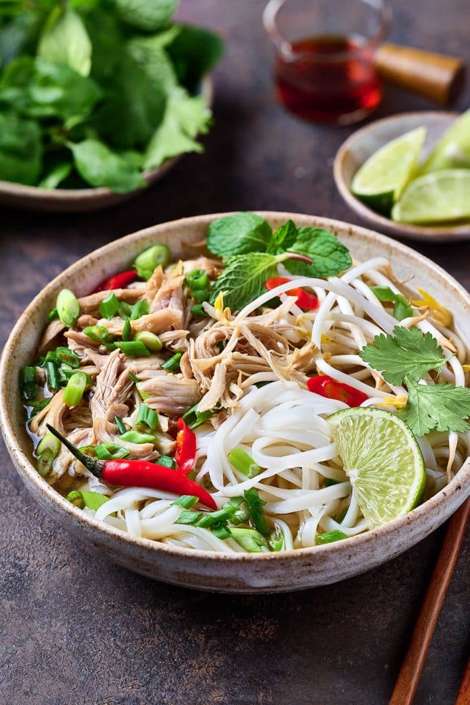 A big bowl of warming chicken pho topped with bean sprouts and herbs.