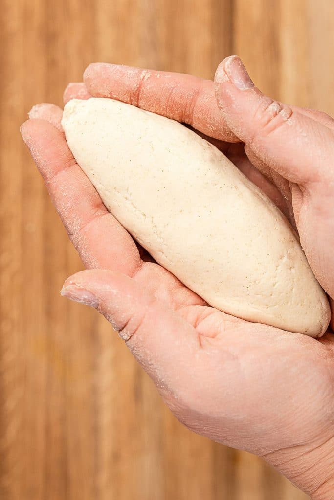 Holding an oval, football like piece of corn dough