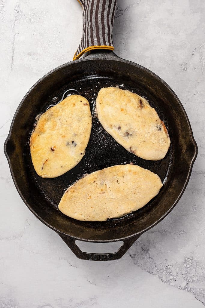Pan frying tlacoyos in a cast iron skillet.