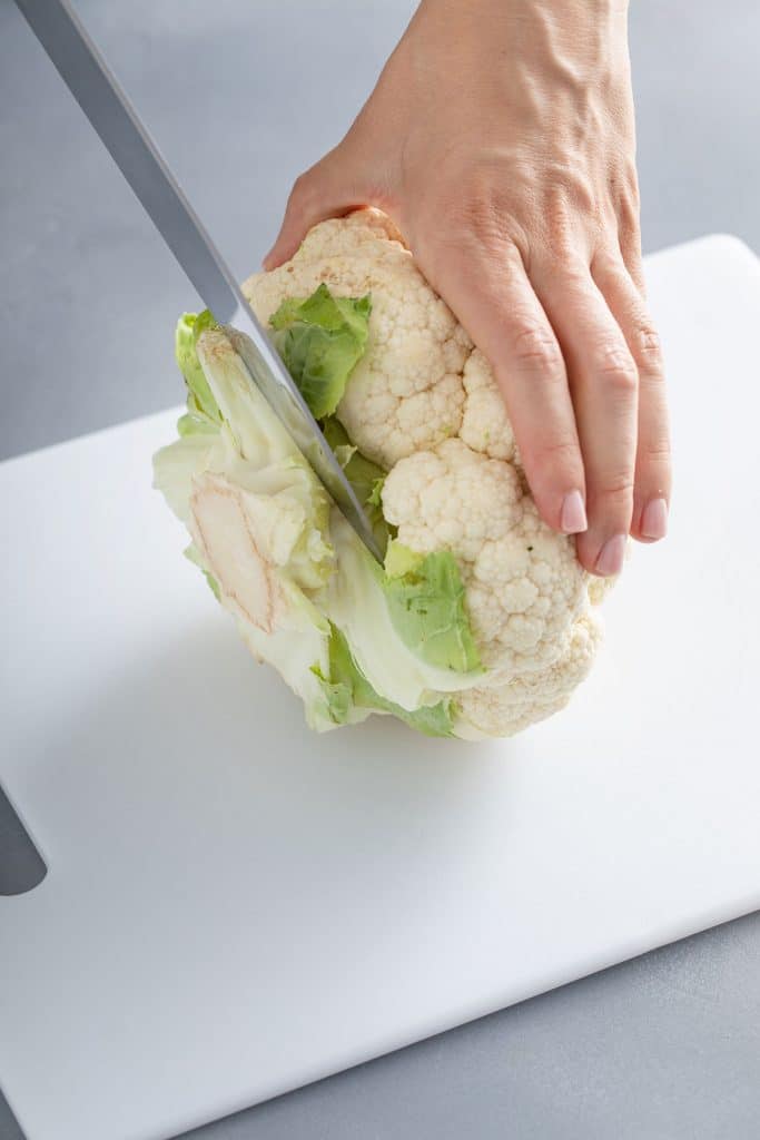 Cutting the base of a whole cauliflower head