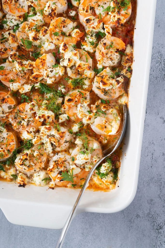 close up view of greek shrimp with tomatoes and feta in a baking dish
