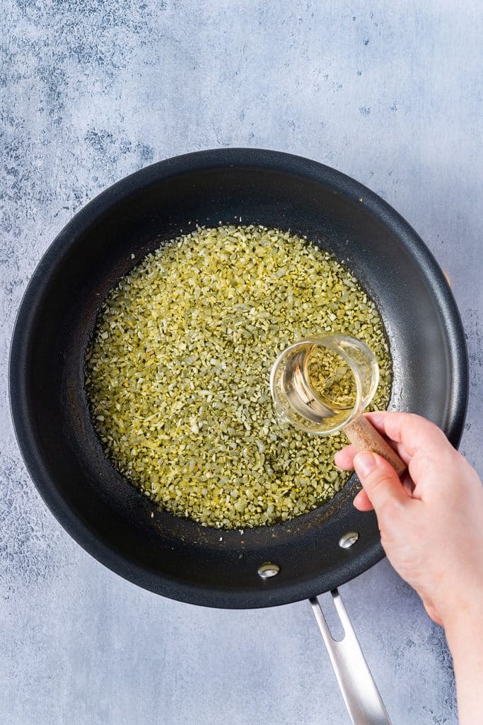 pouring greek ouzo over the cooked onion