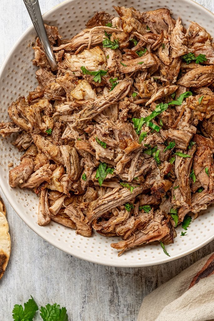 crispy slow cooker carnitas in a large bowl garnished with cilantro