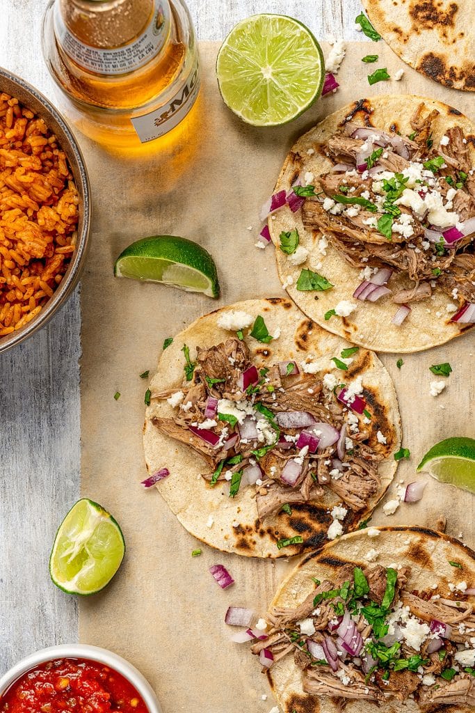 crispy slow cooker carnitas served with feta cheese and onions over corn tortillas.
