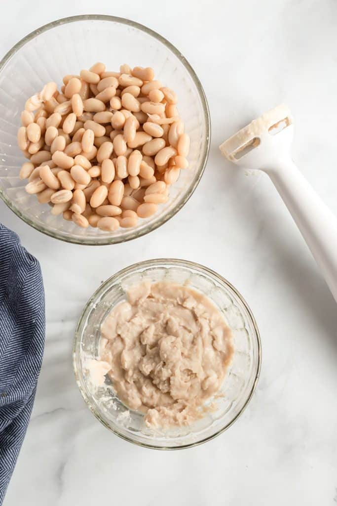 mashed beans in a small bowl next to an immersion blender 