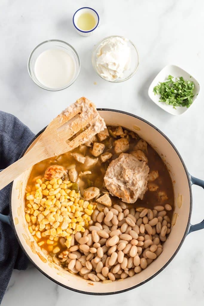chicken simmering in chicken broth, with beans and corn