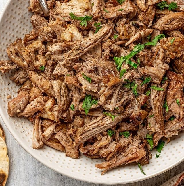 crispy slow cooker carnitas in a large bowl garnished with cilantro