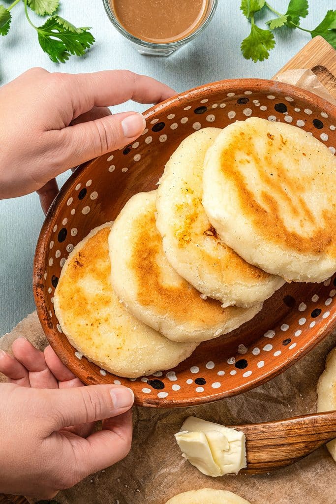 top view of four arepas con queso in a brown dotted bowl
