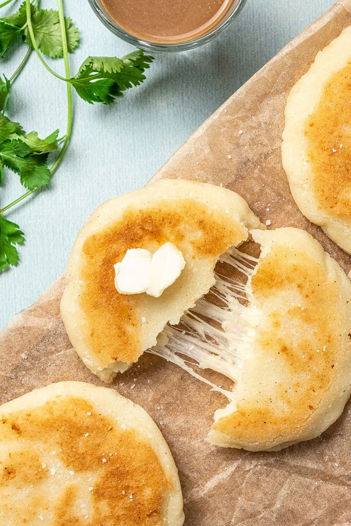 top view of an arepa cut in half with melted cheese inside