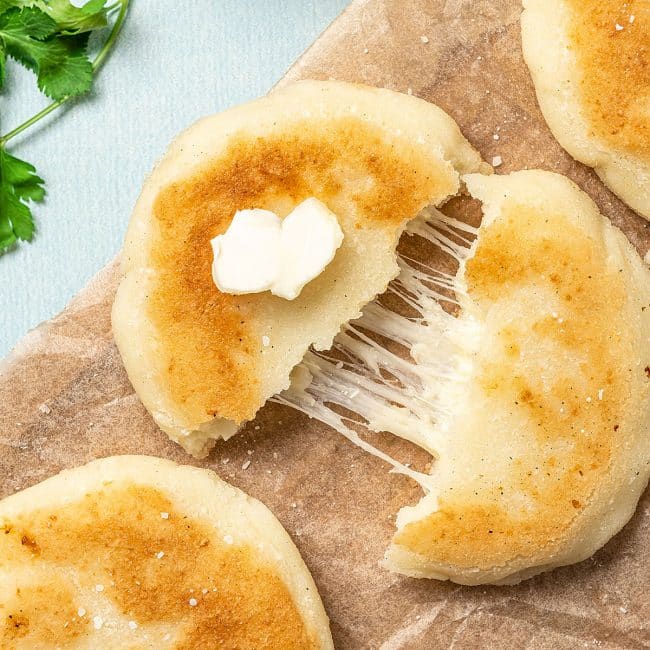 top view of an arepa cut in half with melted cheese inside