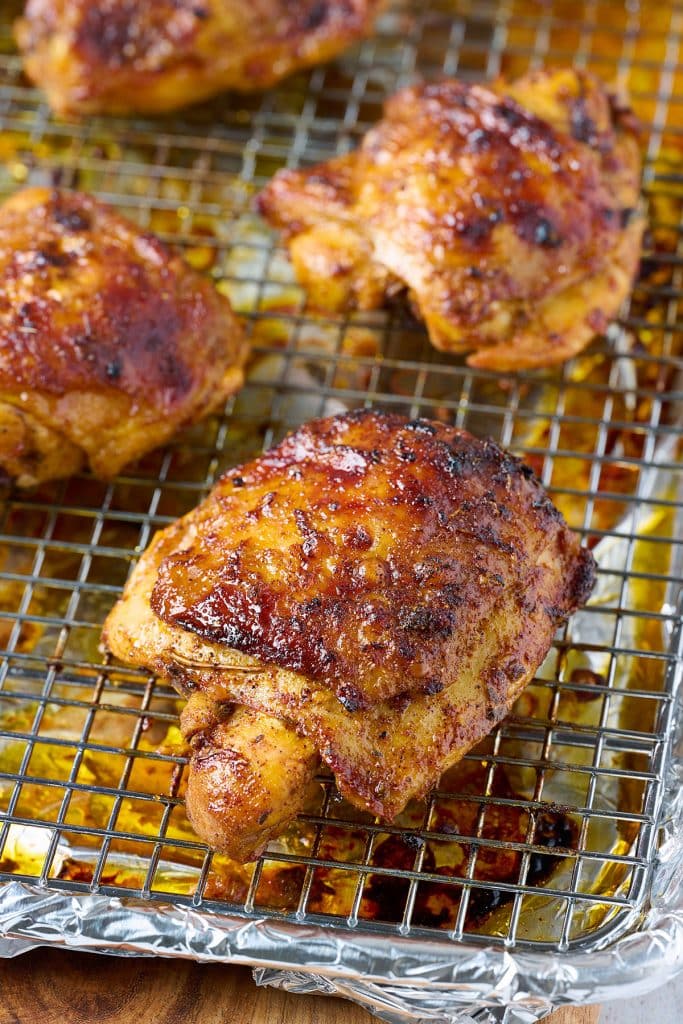 Golden brown pollo asado chicken thighs on a wire rack.