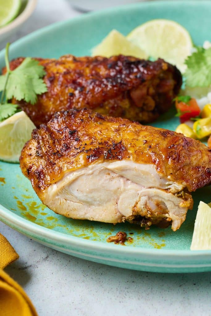 Golden brown cooked pollo asado cut up and showing its juicy interior.