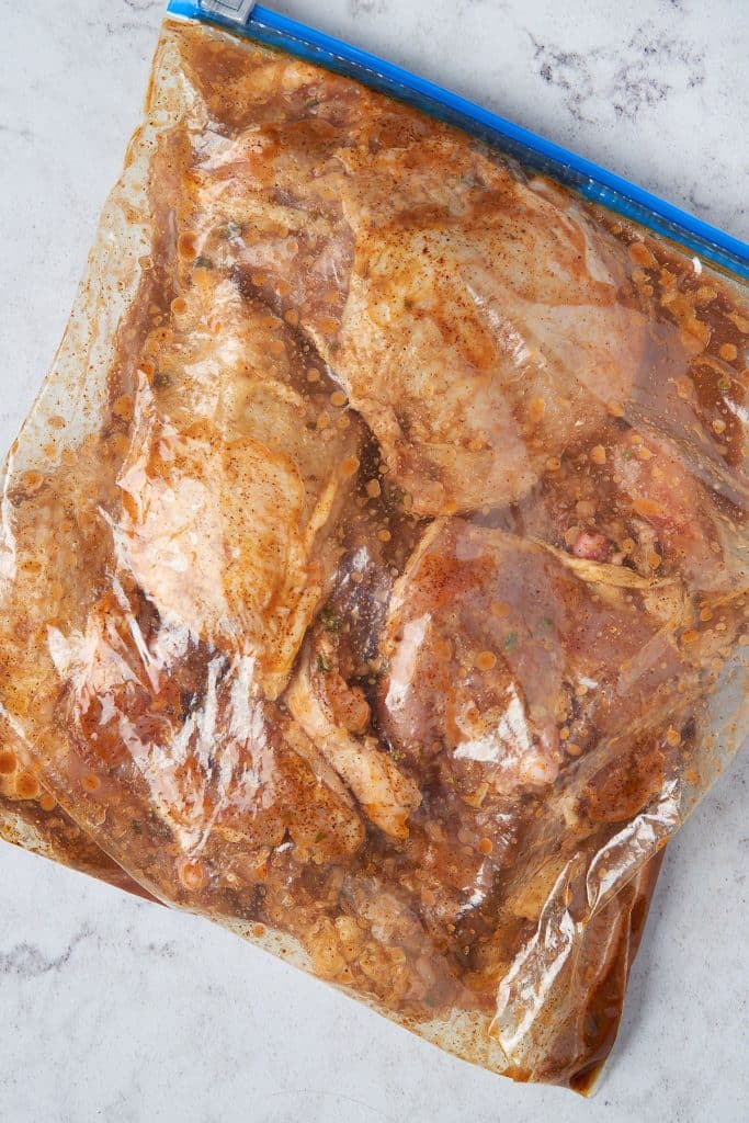Chicken in pollo asado marinade in a resealable bag.