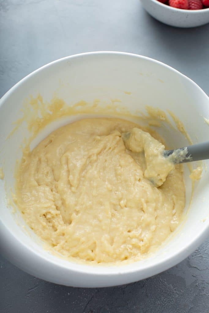 muffin batter in a white bowl with a gray spatula