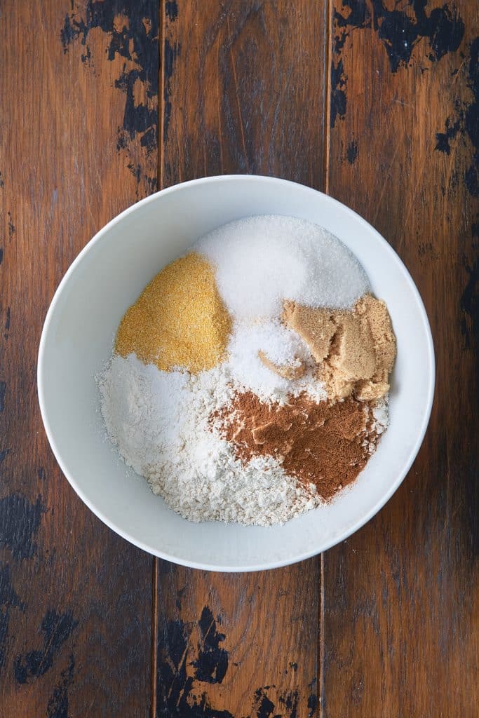 flour, cornmeal, sugar, baking powder, salt, ground cinnamon and pumpkin pie spice in a white bowl