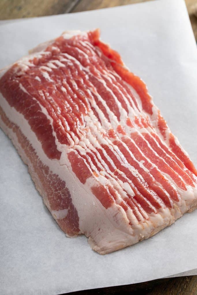 Raw bacon slices on parchment paper