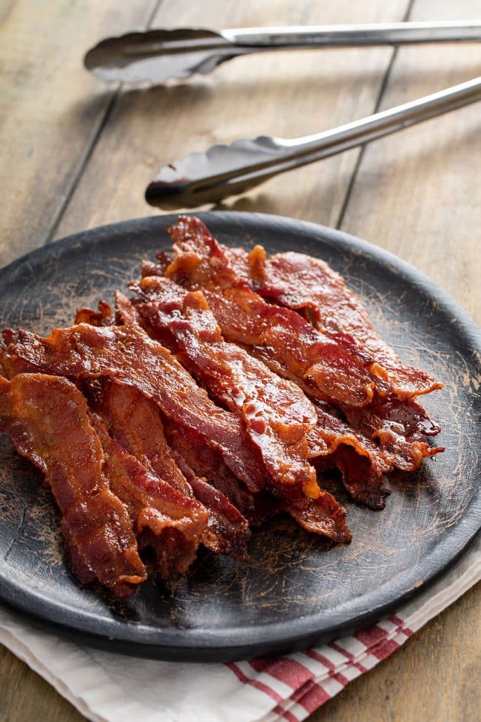 Perfectly baked bacon on a black plate.