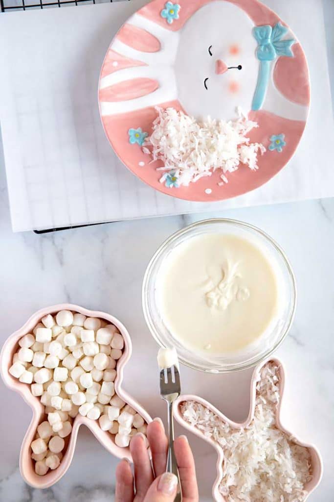 dipping a little marshmallow into melted white chocolate
