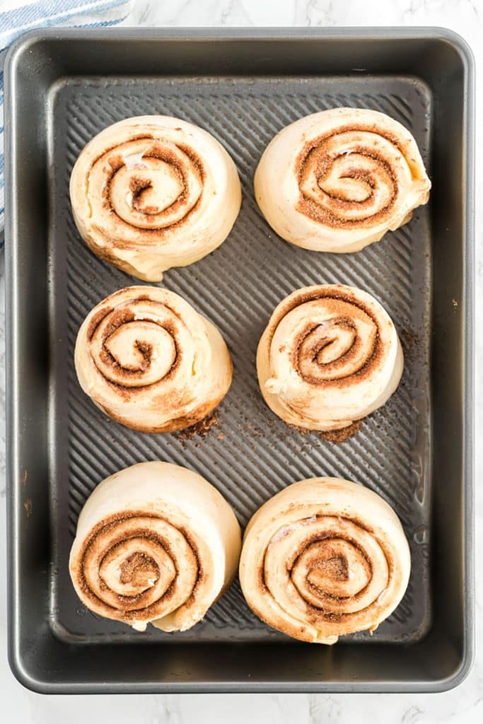 rised cinnamon buns in a baking tray