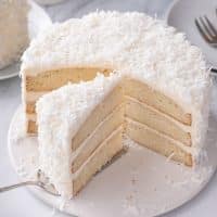 slice of coconut cake being served out of the whole coconut cake