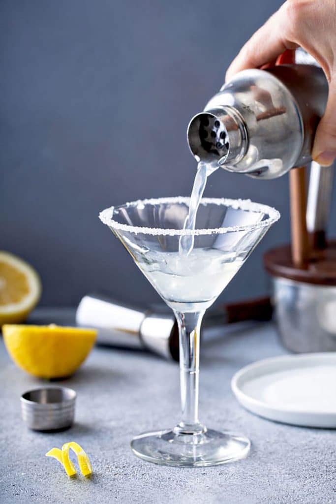 Cocktail shaker pouring lemon martini in a glass