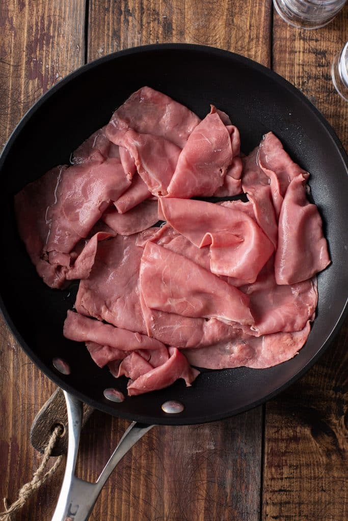 warming up slices of corned beef on a skillet