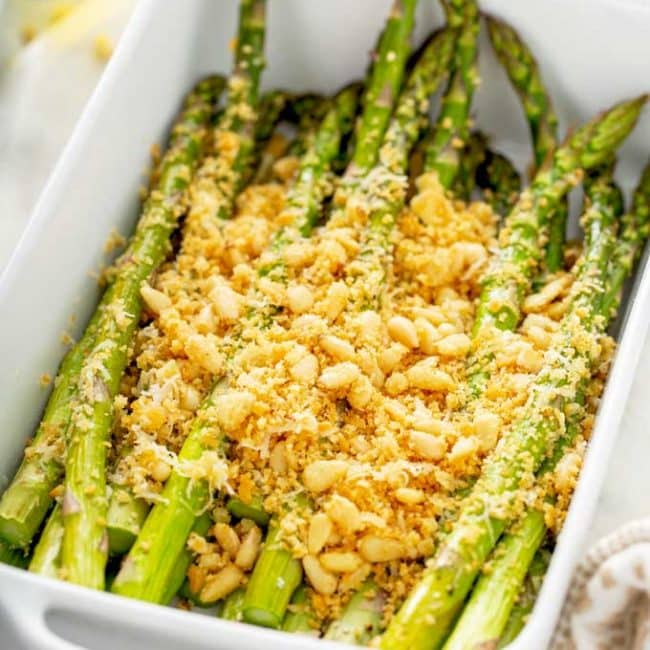 Roasted asparagus with crispy topping on a white plate