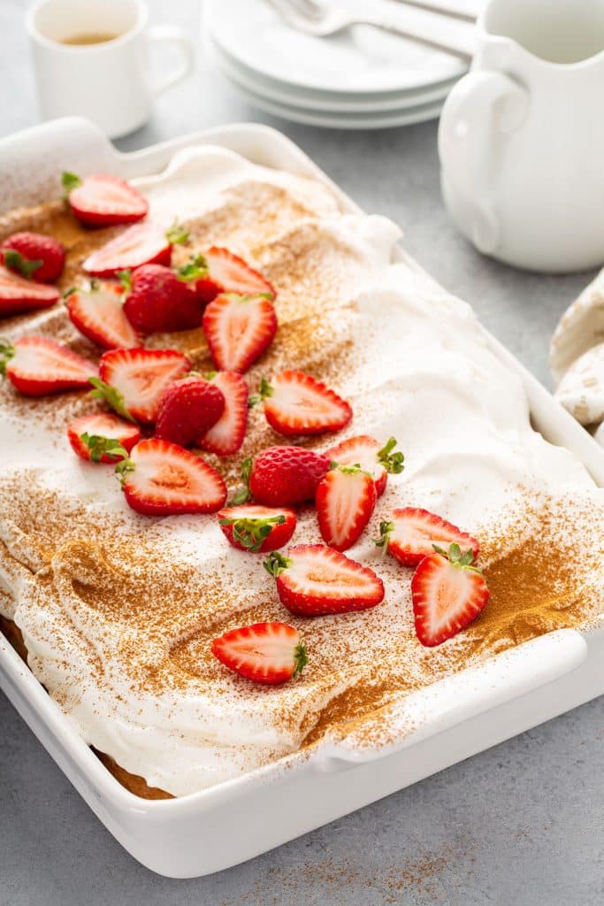 Whole tres leche cake, frosted with cinnamon and halved strawberries