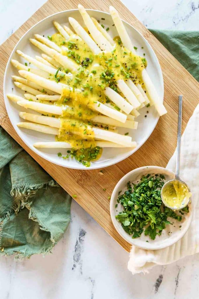 White asparagus covered with Hollandaise  sauce and fresh herbs