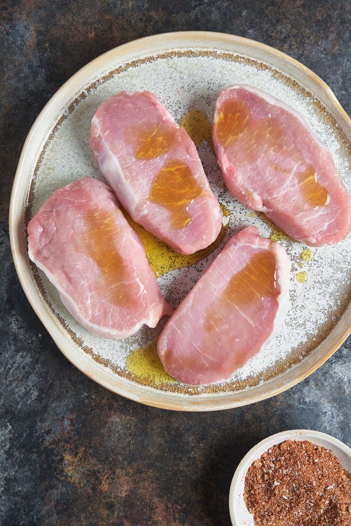 Raw pork chops drizzled with oil