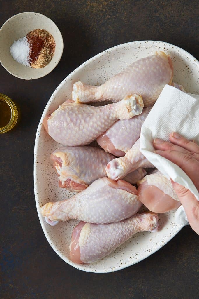 Pat drying raw chicken pieces with paper towels