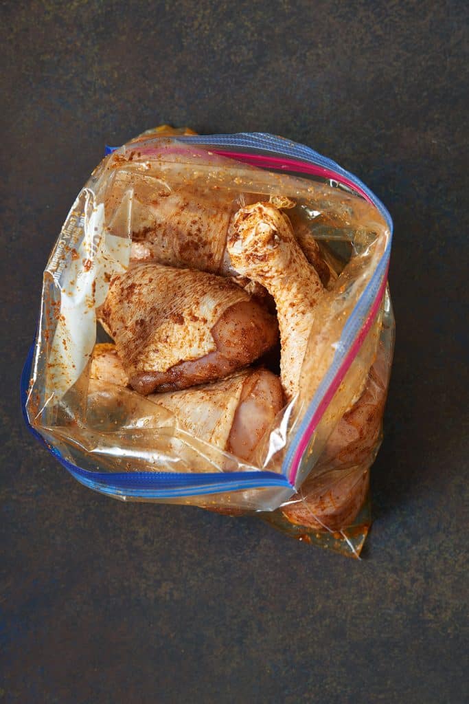 Seasoned raw chicken legs in a resealable bag