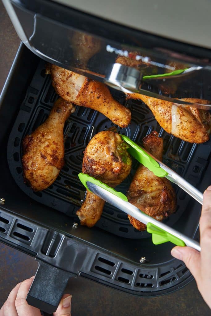 Flipping chicken legs with kitchen tongs