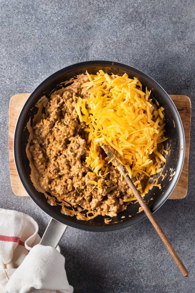 Beef mixture topped with shredded cheese in a skillet.