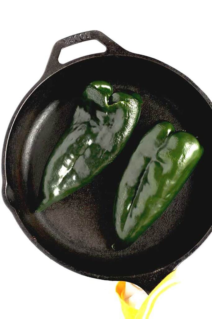 charting 2 poblano peppers in a cast iron skillet