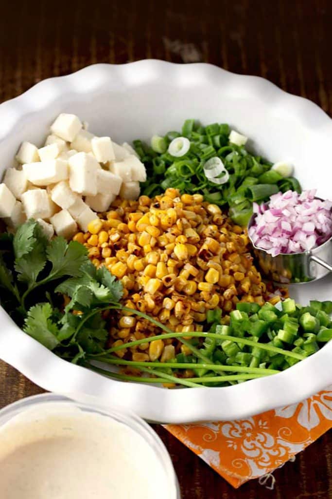 roasted corn, jalapenos, green onions, red onions, cilantro and Cotija cheese in a large white bowl