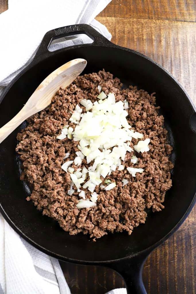 cooking ground beef on a skillet with chopped onions