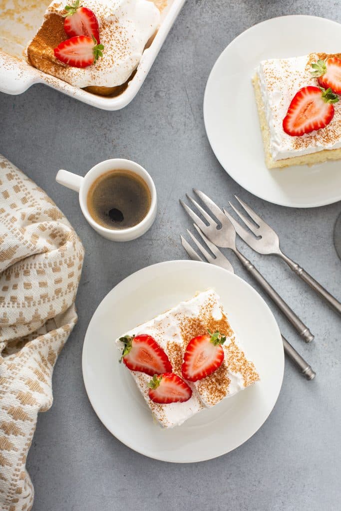 Top view of slices of cake garnished with cinnamon and strawberries on white plates