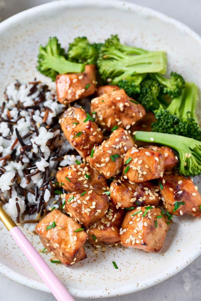 salmon nuggets coated with sesame seeds, broccoli, and wild rice on a plate