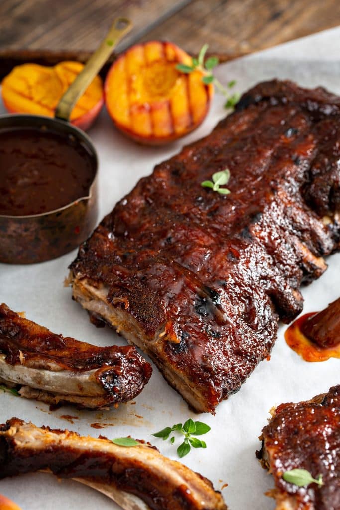 baked ribs rack smothered in bbq sauce and a few singe rib cut out showing the tender meat