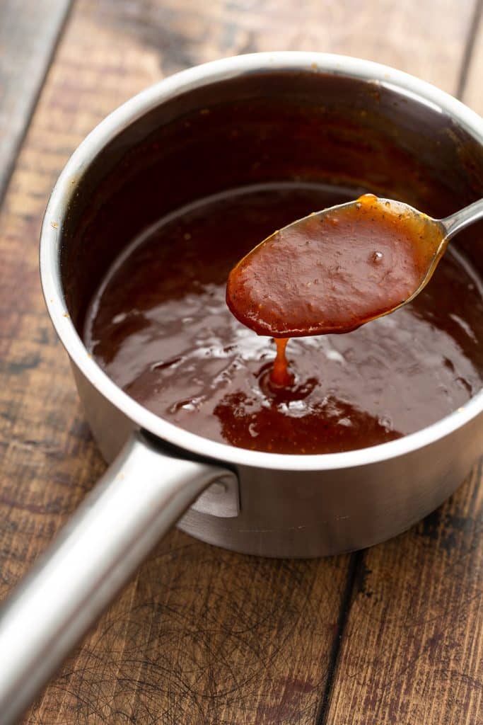 peach bourbon bbq sauce in a saucepan with a spoon