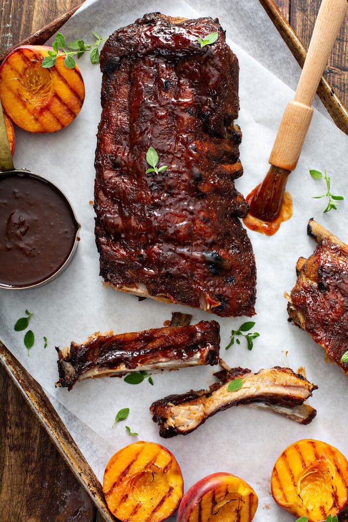 The secret to fall-off-the-bone tender baby back ribs or spare ribs is to oven bake them low and slow. This easy recipe, delivers flavorful and tender oven-baked ribs, that are perfectly seasoned with a simple homemade spice rub and smothered in the tastiest Bourbon-Peach BBQ sauce. 