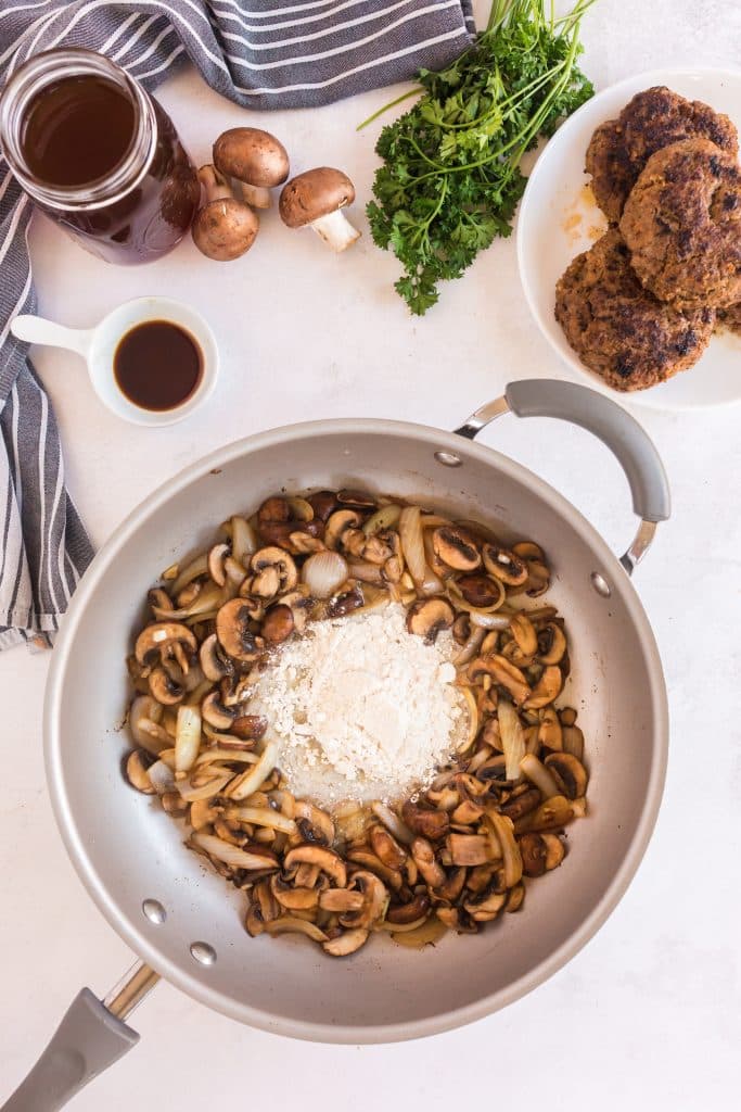 flour in the center of a skillet and caramelized onions and mushrooms around it