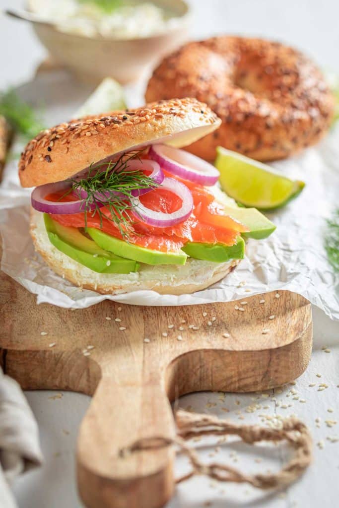 Bagel with sliced avocado, smoked salmon, onion and dill