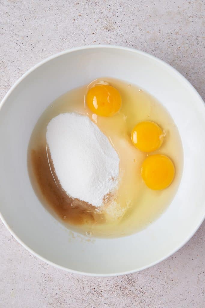 Eggs, vanilla and sugar in a white bowl