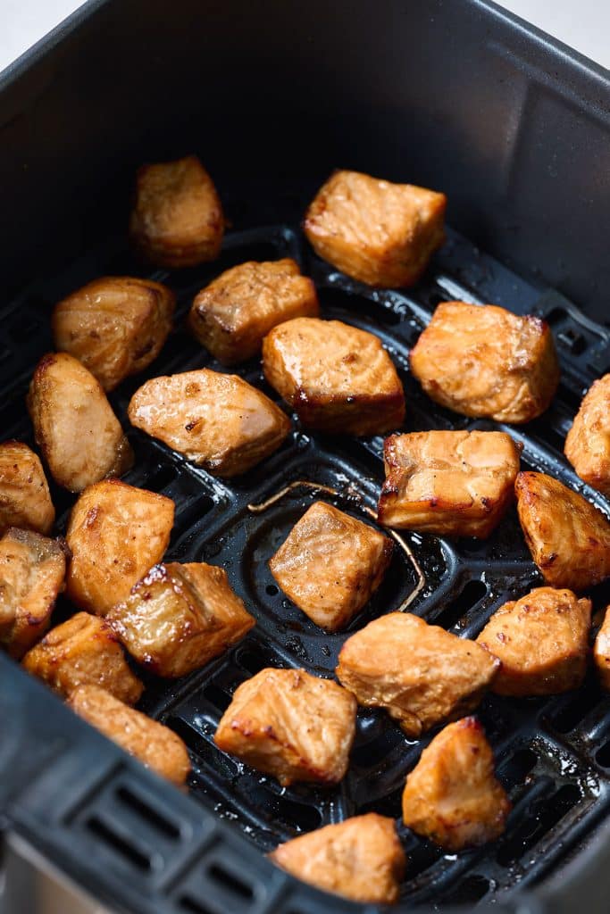 Cooked salmon bites in an air fryer basket
