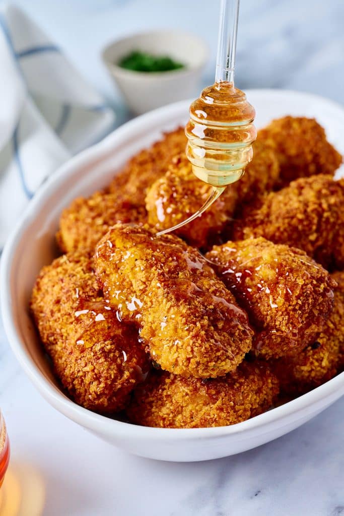 crispy chicken being drizzled with honey